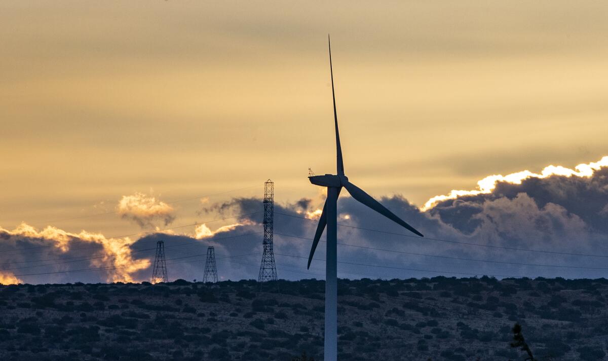A wind turbine rises above a desert landscape. 