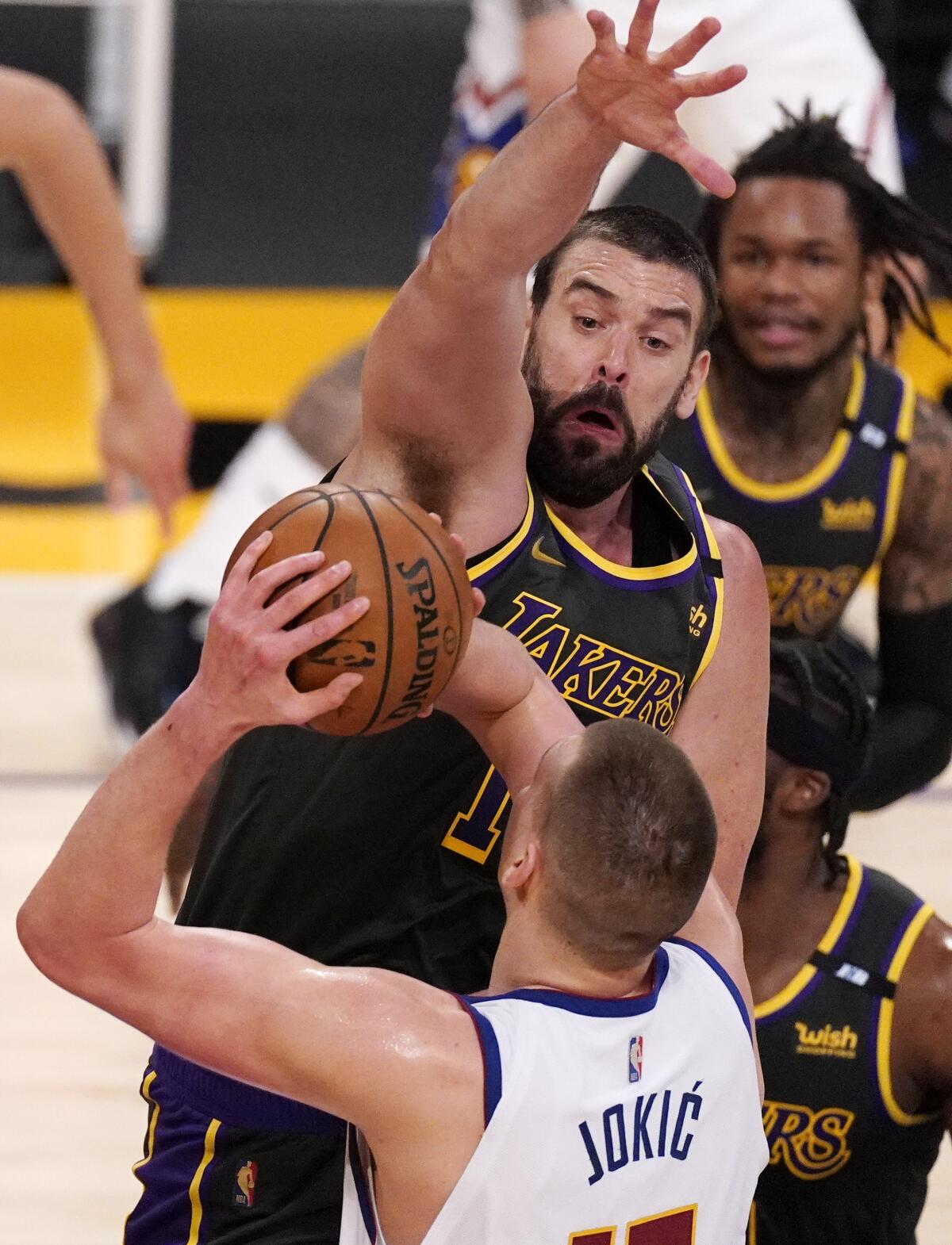 Lakers center Marc Gasol reaches above Nuggets center Nikola Jokic.