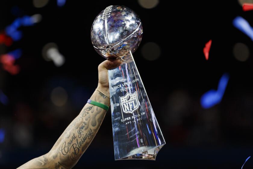 The Vince Lombardi Trophy with confetti falling as it's held up by New England Patriots strong safety Patrick Chung (23) after NFL Super Bowl 53 against the Los Angeles Rams on Sunday, Feb. 3, 2019 in Atlanta. The Patriots defeated the Rams, 13-3. (Ryan Kang via AP)