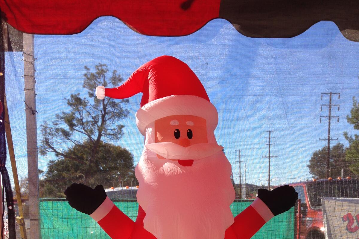 An inflatable Santa Claus sitting on a bale of straw.