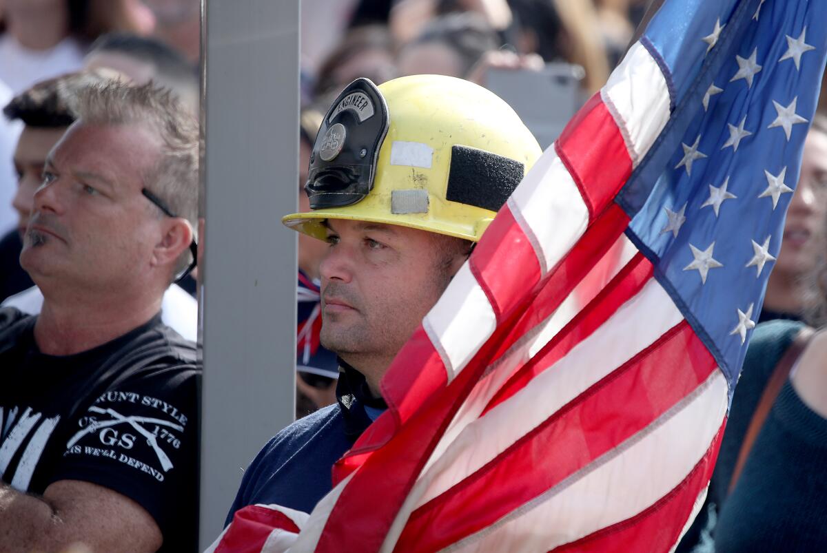 A protester in a firefighter's helmet holds an American flag
