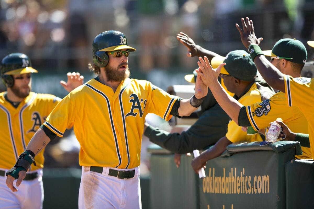 Oakland's Josh Reddick celebrates with his teammates after scoring a run during the Athletics' 11-7 win over the Minnesota Twins on Sunday.