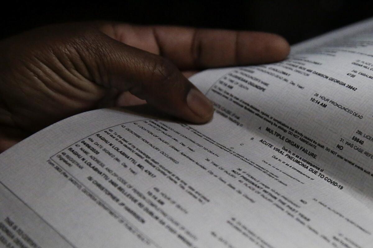 A woman's left hand holds a death certificate.