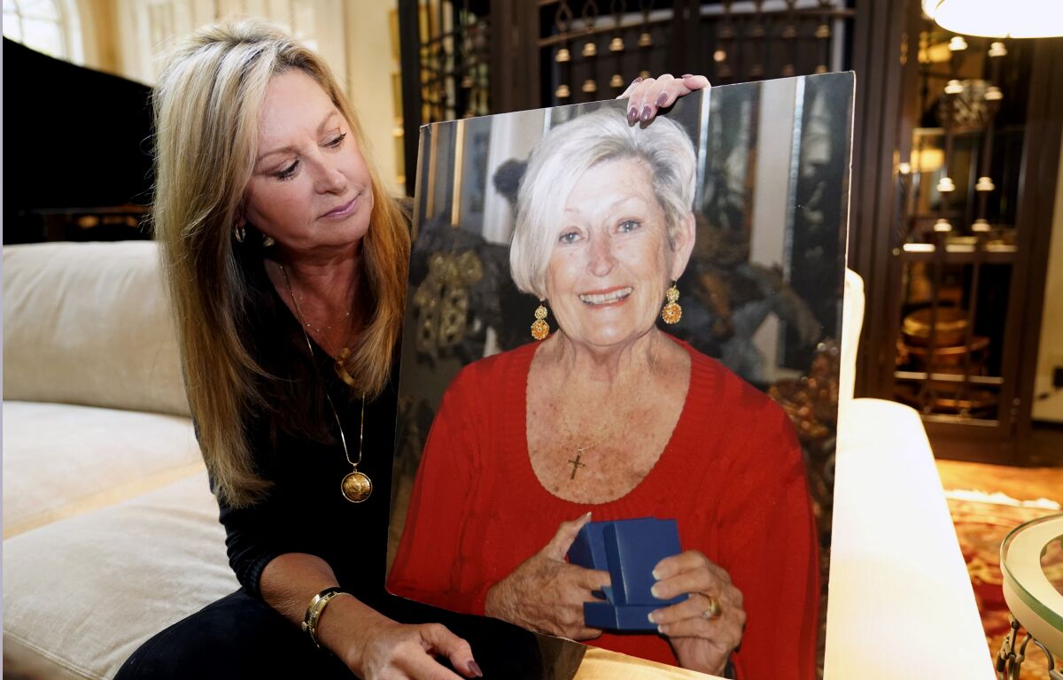 M.J. Jennings looks at a photo of her mother Leah Corken while sitting at her home in Dallas, Wednesday, Nov. 3, 2021. Corken was one of 18 women in the Dallas area that Billy Chemirmir is charged with capital murder and he is suspected in several more deaths. Most of the deaths happened at upscale independent living communities for older people, where Chemirmir has been accused of forcing his way into apartments or posing as a handyman, and in a couple instances was even caught trespassing. (AP Photo/LM Otero)
