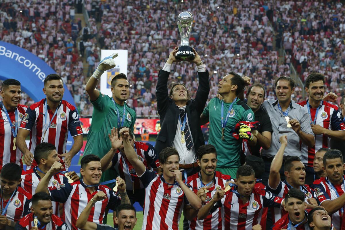 Chivas' coach Matias Almeyda holds the trophy as the team celebrates its win over Tigres for the Mexican soccer league championship in Guadalajara, Mexico, Sunday, May 28, 2017. (AP Photo/Eduardo Verdugo)