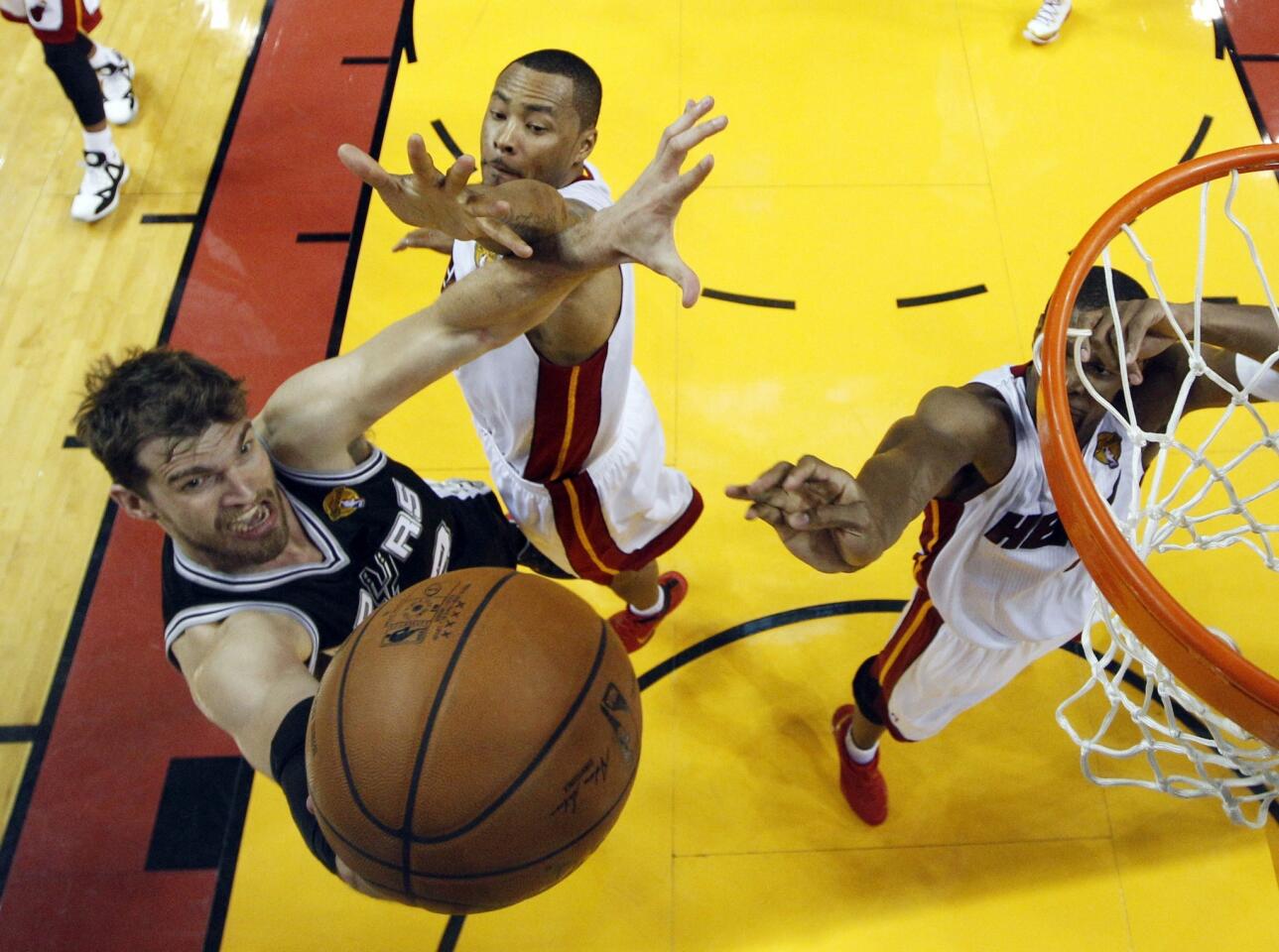 San Antonio Spurs center Tiago Splitter, right, puts up a shot over Miami Heat teammates Rashard Lewis, center, and Chris Bosh during the first half of Game 3 of the NBA Finals.