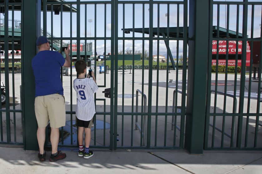 Fans take photos through the locked gates at the Cactus League's Sloan Park, the spring training site of the Chicago Cubs.