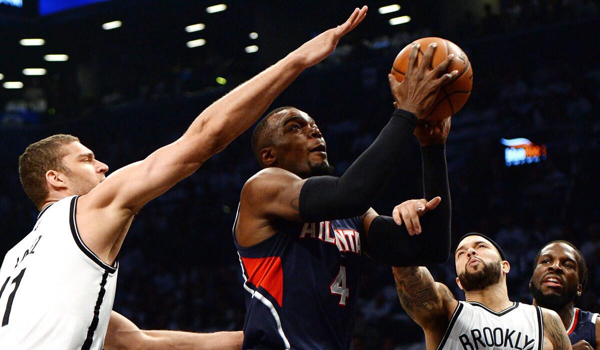 Hawks' Paul Millsap drives to the basket past the Nets' Brook Lopez and Deron Williams during the Hawks' 111-87 win over the Nets. The Hawks win the series, 4-2.