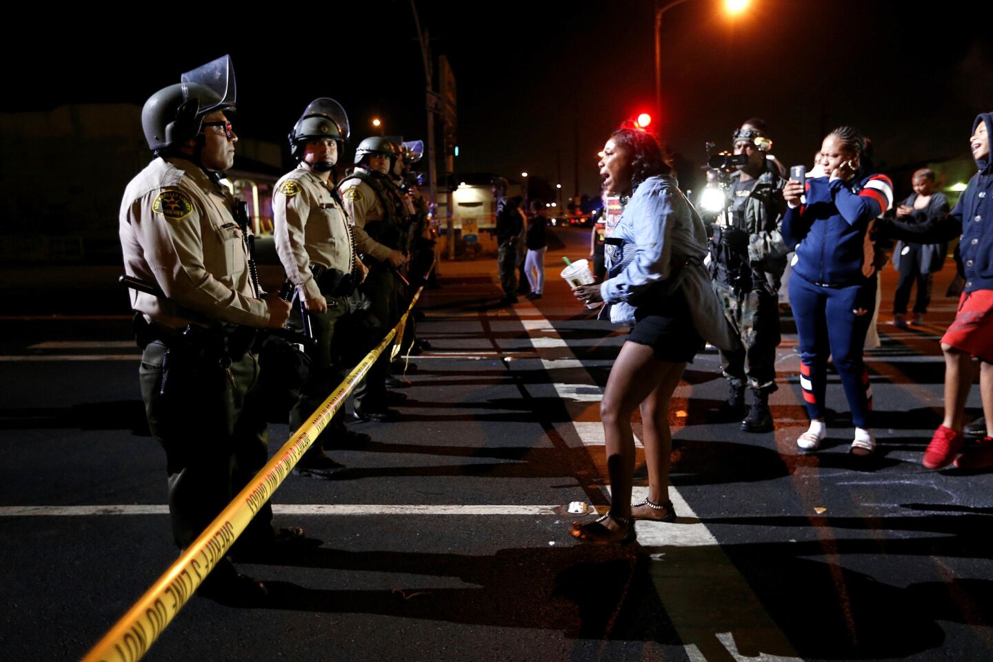 A women confronts the LA County Sheriif blocking the street after a vigil is held for Carnell Snell Jr., 18, who was fatally shot by LAPD police Saturday after a vehicle pursuit, in Los Angeles.