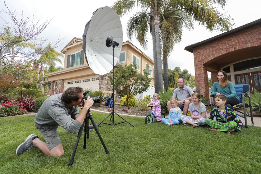 Professional photographer John Riedy prepares to photograph Drew Nichols, his wife Delia, and children, from left, Claire, 2, Anna, 5, Sarah, 11, and Jacob, 8, as part of his time capsule portraits series documenting families during the coronavirus pandemic on Thursday, April 2, 2020 in Carlsbad, California.