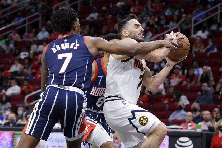 Houston Rockets guard Armoni Brooks, left, fouls Denver Nuggets guard Facundo Campazzo during the first half of an NBA basketball game Saturday, Jan. 1, 2022, in Houston. (AP Photo/Michael Wyke)