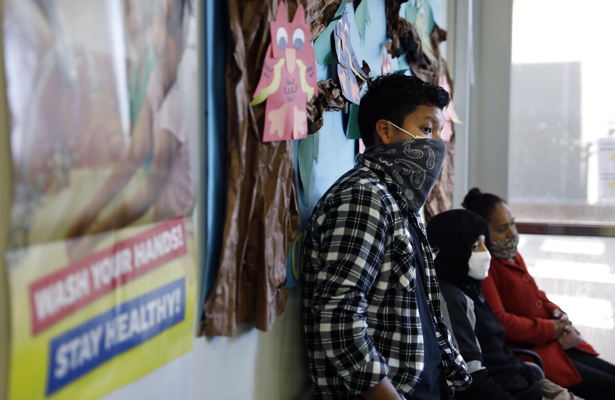 Students wait to pick up computers at Linda Esperanza Marquez High School in Huntington Park as the L.A. school district transitioned to online learning in response to the coronavirus pandemic.