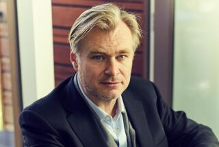 Christopher Nolan sitting in a chair with his hands on his lap