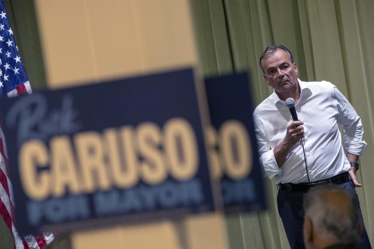 Los Angeles mayoral candidate Rick Caruso listens and holds a microphone.