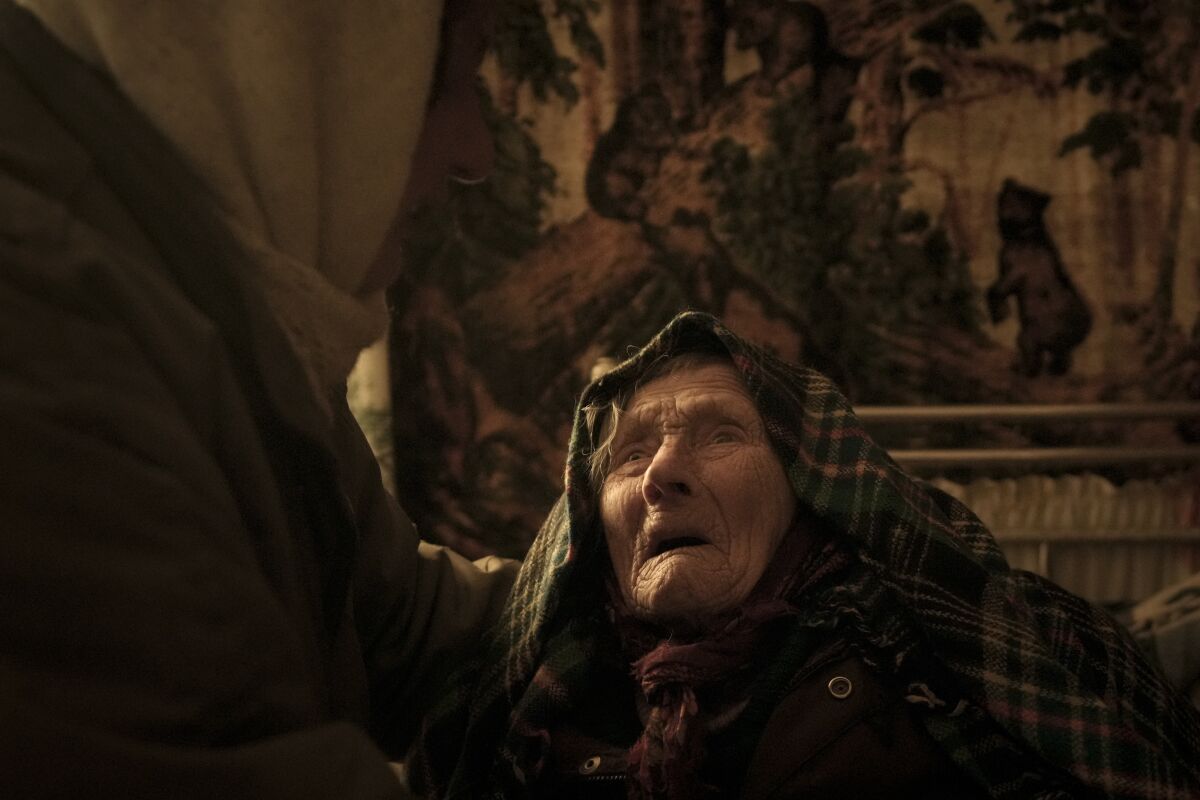Motria Oleksiienko, 99, traumatized by the Russian occupation, is comforted by daughter-in-law Tetiana Oleksiienko in a room without heating in the village of Andriivka, Ukraine, heavily affected by fighting between Russian and Ukrainian forces, Wednesday, April 6, 2022. (AP Photo/Vadim Ghirda)