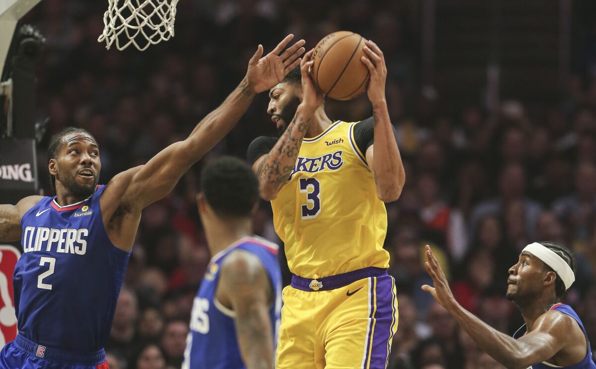 Lakers forward Anthony Davis grabs a rebound against Clippers forward Kawhi Leonard during the season opener on Oct. 22.