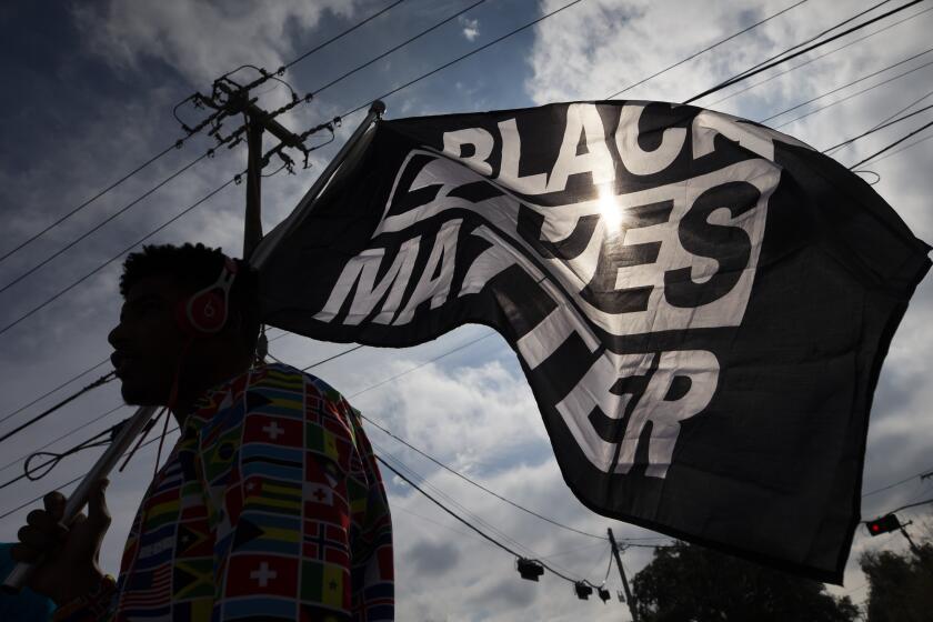 FILE - In this Dec. 12, 2020, file photo, MD Crawford carries a Black Lives Matter flag before a march in La Marque, Texas to protest the shooting of Joshua Feast, 22, by a La Marque police officer. A financial snapshot shared exclusively with The Associated Press shows the Black Lives Matter Global Network Foundation raked in just over $90 million last year. (Stuart Villanueva /The Galveston County Daily News via AP, File)