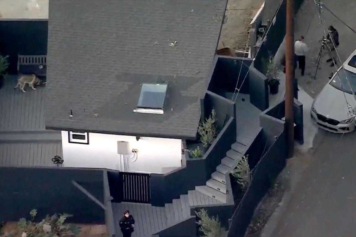 An aerial view of a house in Hollywood Hills with police officers standing nearby