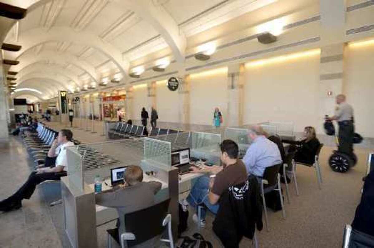 The FCC is promising more access to high-speed WiFi at airports and convention centers. Above, travelers at Orange County's John Wayne Airport use laptops at the terminal.