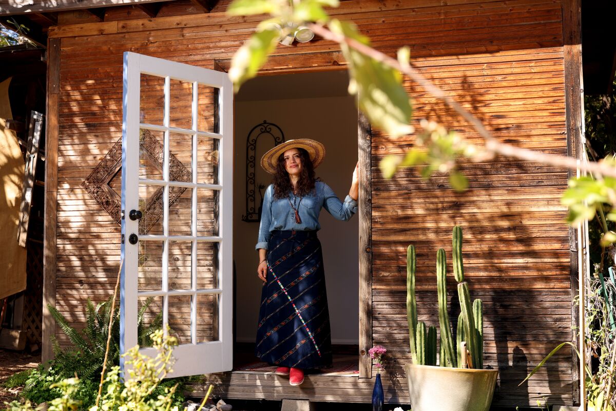 A woman stands in a doorway looking out into a garden.
