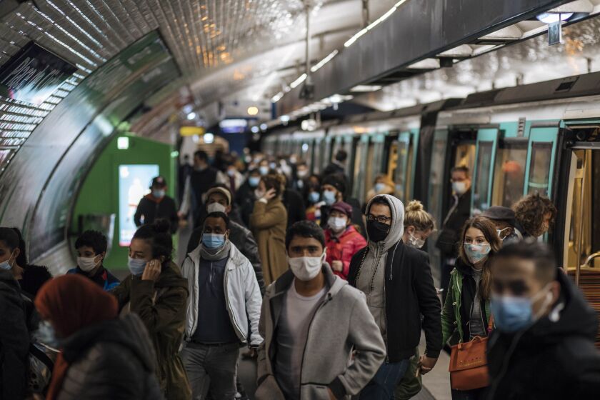 Commuters wearing face masks walk on the platform, of a Paris subway, Sunday Oct.25, 2020. A curfew intended to curb the spiraling spread of the coronavirus, has been imposed in many regions of France including Paris and its suburbs. (AP Photo/Lewis Joly)