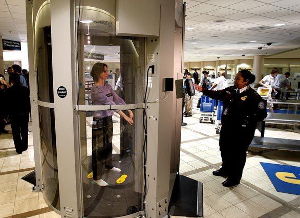 Evelina Ahsan, right, an officer with the federal Transportation Security Administration, participates in a demonstration of the new WBI Millimeter Wave Whole Body Imaging Technology at Terminal 5 at Los Angeles International Airport today. TSA officials say the machine will be used to randomly screen airline passengers.