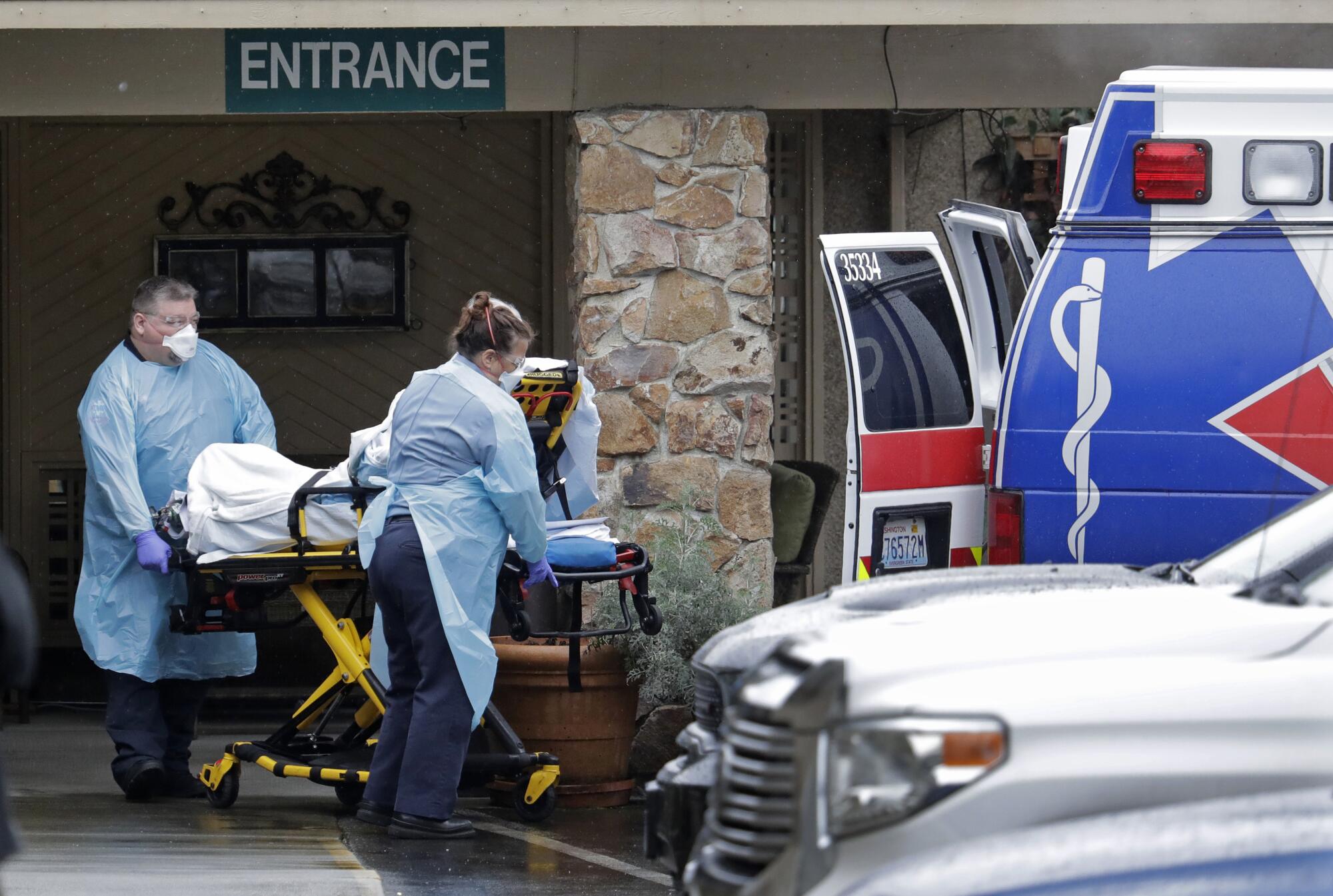 Ambulance workers move a man on a stretcher from the Life Care Center in Kirkland, Wash., into an ambulance.