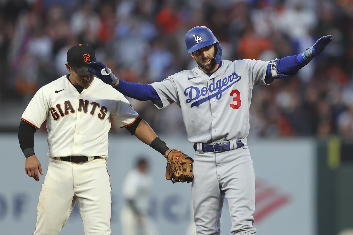 Los Angeles Dodgers' Chris Taylor (3) gestures next to San Francisco Giants' Donovan Solano after hitting a double during the second inning of Game 2 of a baseball National League Division Series Saturday, Oct. 9, 2021, in San Francisco. (AP Photo/John Hefti)