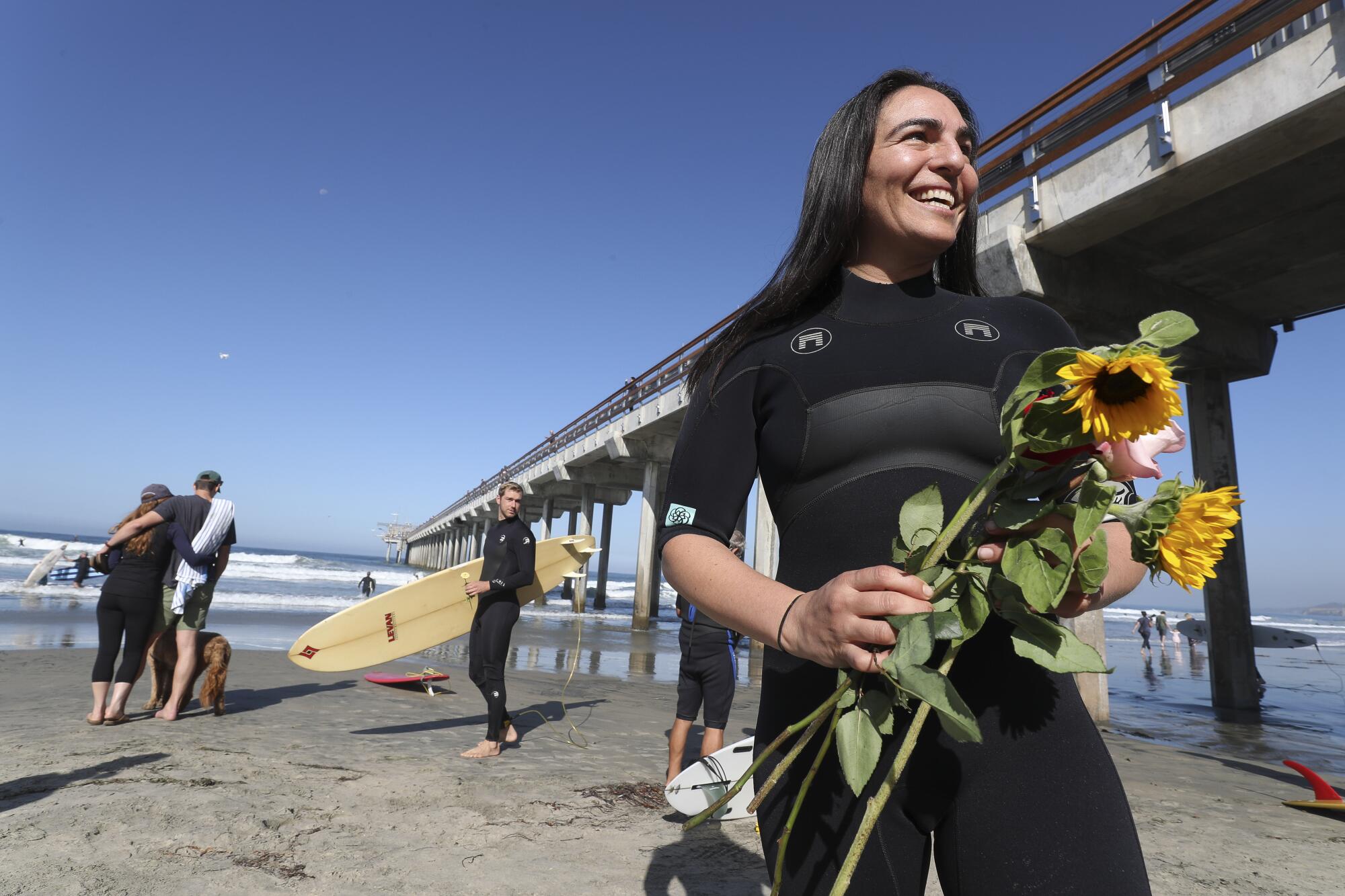 Luka Spear holds flowers before participating in a paddle out for Scripps oceanographer Walter Munk 