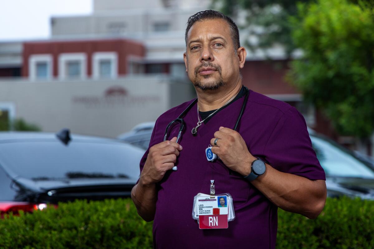 Leo Perez stands in purple scrubs outside near cars