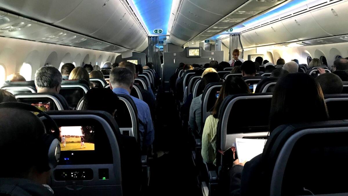 Airline passengers pass the time aboard a 2018 flight. The next step in in-flight entertainment may be a personalized offering that draws from each passenger's loyalty-program profile.