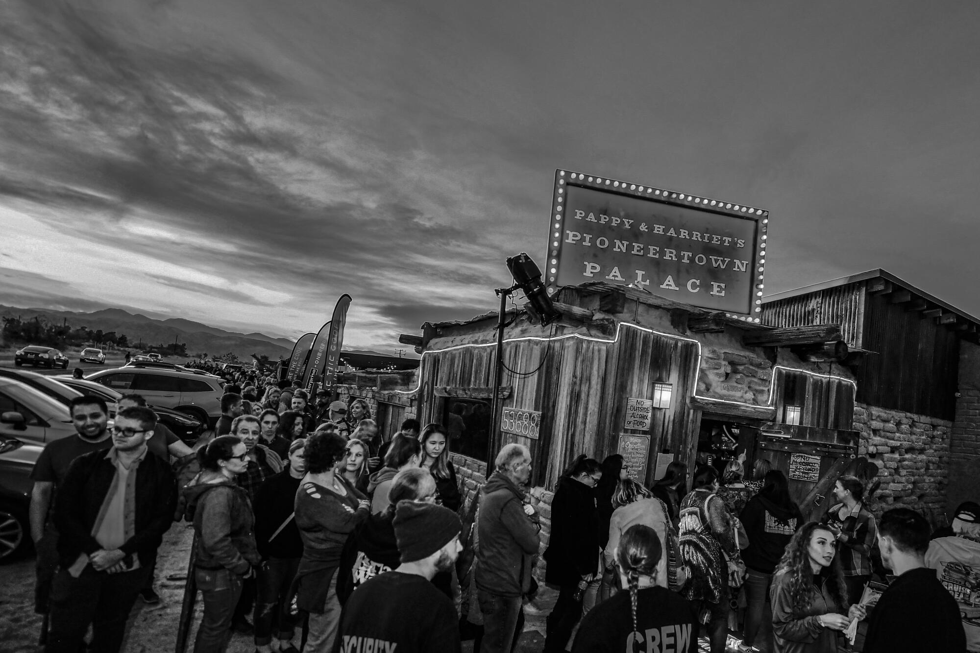 A crowd of people standing outside a saloon/nightclub.