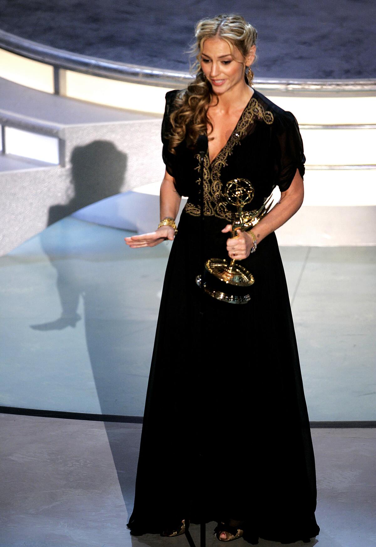 Actor Drea de Matteo wears a black gown and holds an Emmy on stage.