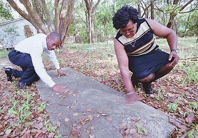Shelton Chappell and his sister Jacqueline Williams brush leaves off the cement cover of their mother's grave in an unkept cemetery in Jacksonville, Fla. Johnnie Mae Chappell was killed in 1964 by four white men during a week of racial tension in Jacksonville.