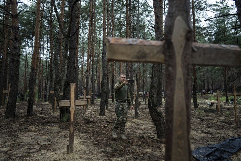 Oleg Kotenko, the Commissioner for Issues of Missing Persons under Special Circumstances uses his smartphone to film the unidentified graves of civilians and Ukrainian soldiers in the recently retaken area of Izium, Ukraine, Thursday, Sept. 15, 2022 who had been killed by Russian forces near the beginning of the war. A mass grave of Ukrainian soldiers and unknown buried civilians was found in the forest of recently recaptured city of Izium. (AP Photo/Evgeniy Maloletka)