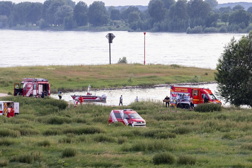 Emergency services of the police, fire brigade and DLRG work on the banks of the Rhine, in Duisburg, Germany, Wednesday, June 16, 2021. One person has been rescued after a possible bathing accident. Two others are still missing. (Marcel Kusch/dpa via AP)