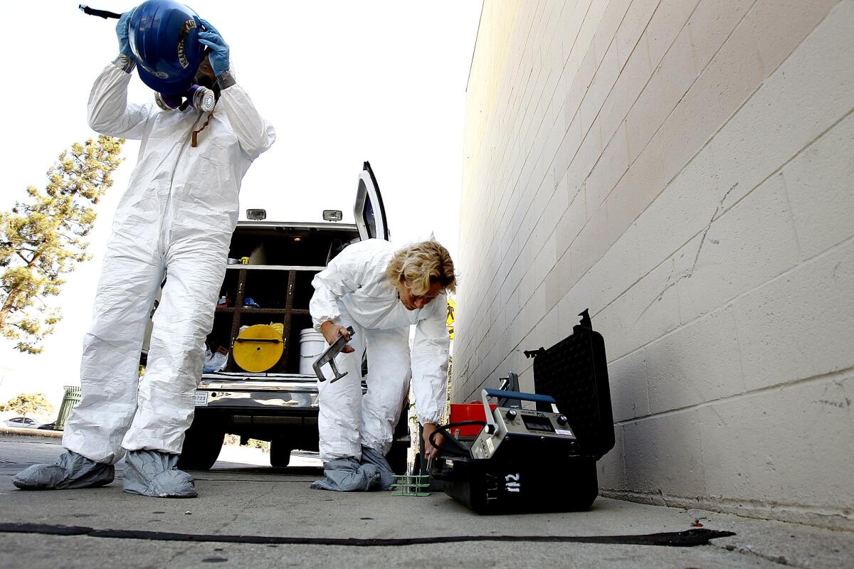 Los Angeles County Fire Department hazardous materials specialists Mario Benjamin, left, and Nancy Parson respond to a call in Whittier to identify an abandoned container in an alley.