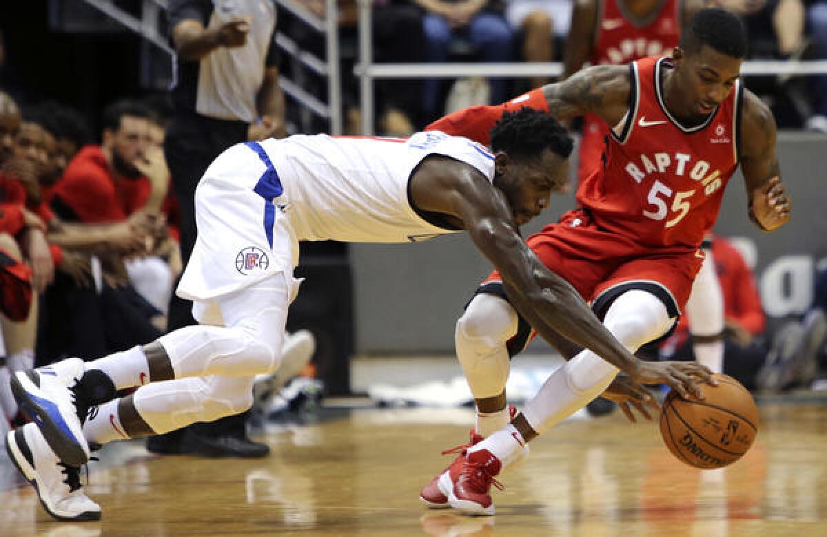 Clippers guard Patrick Beverley dives after a loose ball next to Raptors guard Delon Wright during a preseason game in Honolulu on Oct. 3, 2017.