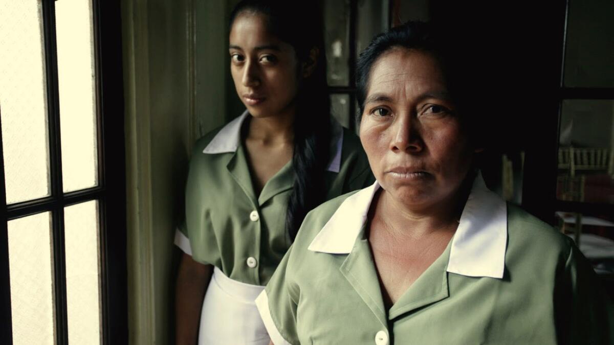 The characters of Alma and Valeriana in housekeeping uniforms in a scene from "La Llorona"