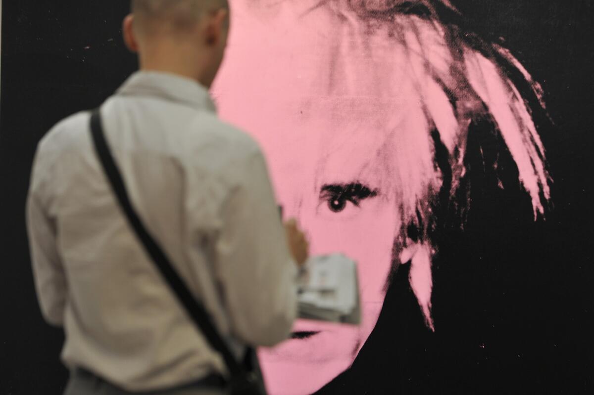 A visitor takes notes in front of the artwork "Self-Portrait" by Andy Warhol at Art Basel in June.