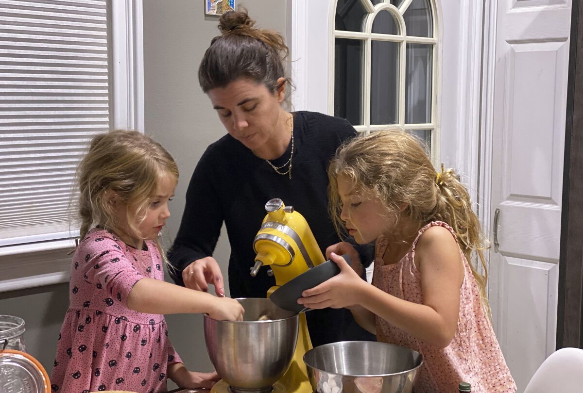 Danielle McWilliams cooks with her daughters Reese, 7, right, and Remi, 4, at their New Jersey home. Along with the usual cupcakes, crispy treats and from-scratch cookies, they make tarallis, an Italian family traditional treat that’s a cross between a breadstick, bagel and pretzel. (Danielle McWilliams via AP)