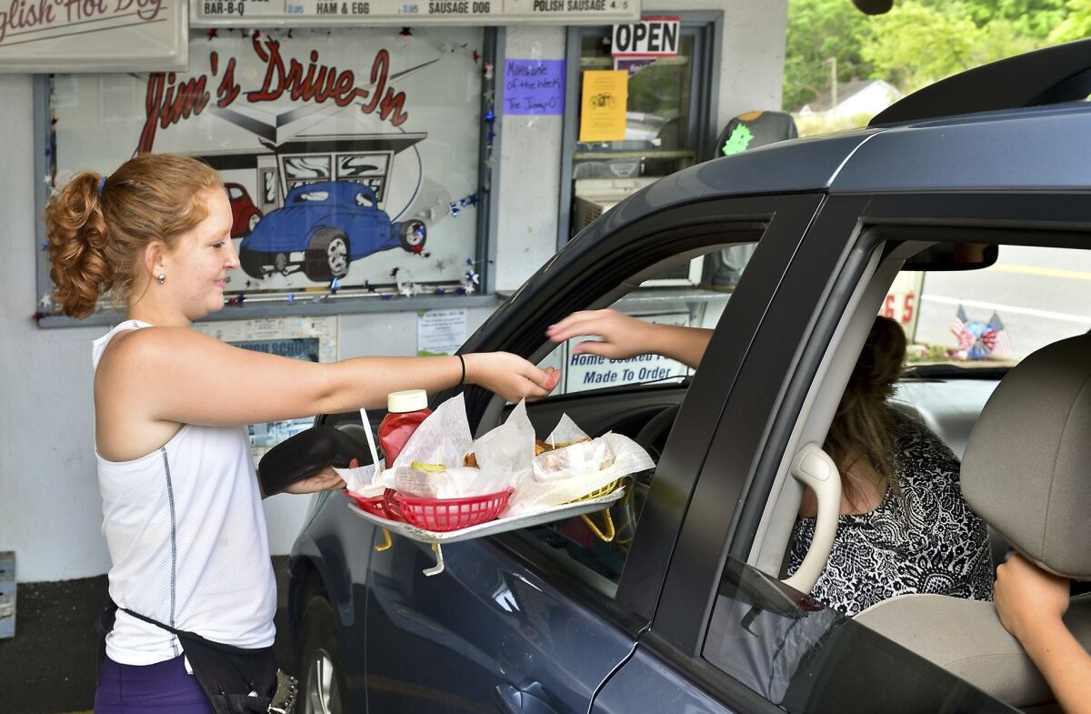 FILE - In this Tuesday June 23, 2015 photo, Jim's Drive-In waitress Aly King delivers an order to a waiting customer at the iconic restaurant in Lewisburg, W.Va. A program offering $20,000 in cash and incentives for remote workers to move to West Virginia as part of a population push has chosen 33 people for its second class of newcomers to live in the Greenbrier Valley, which includes Lewisburg. (Bob Wojcieszak/Daily Mail via AP, File)