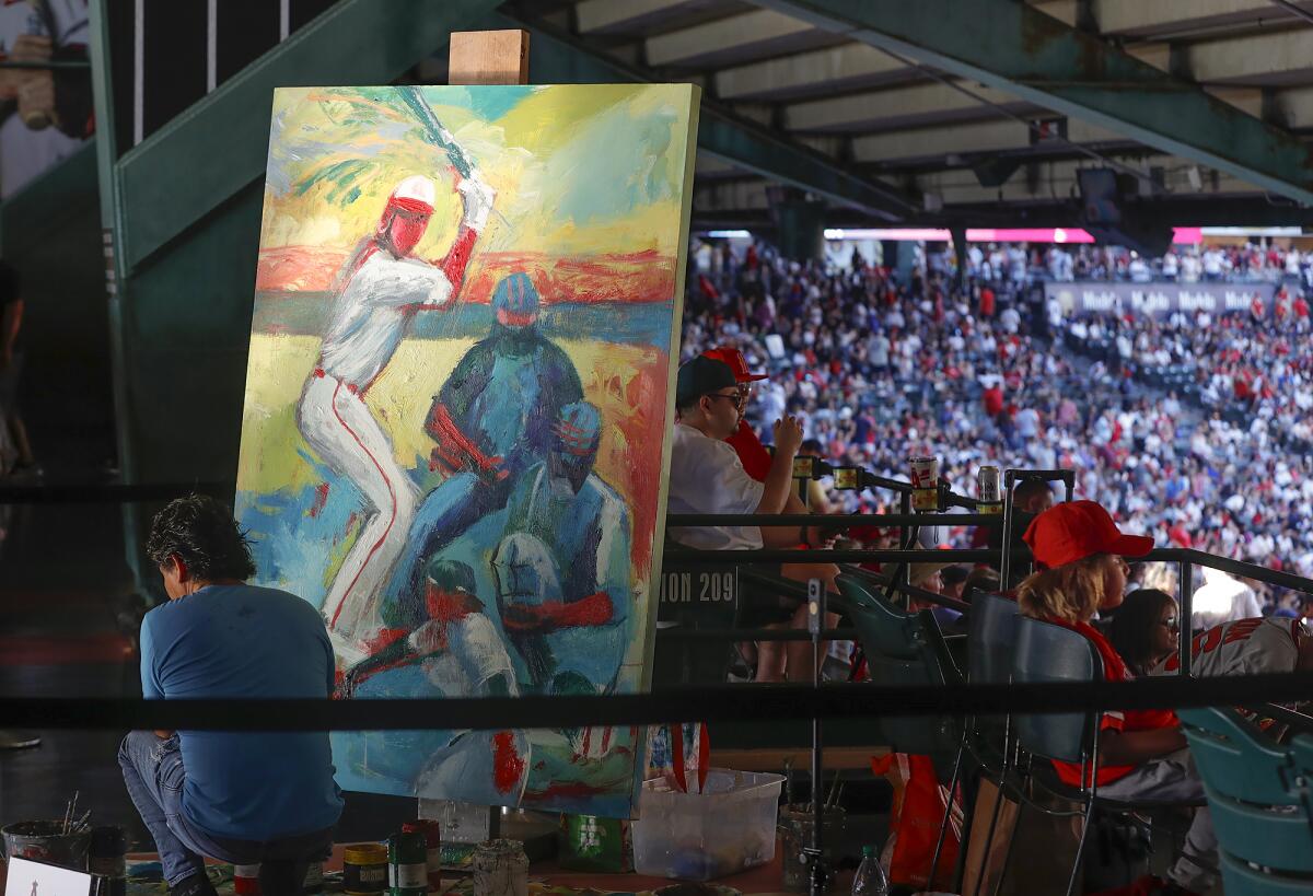 Artist Hugo Rivera, lower left, paints a canvas Wednesday at Angels Stadium, where the Halos beat the Yankees 7-3.
