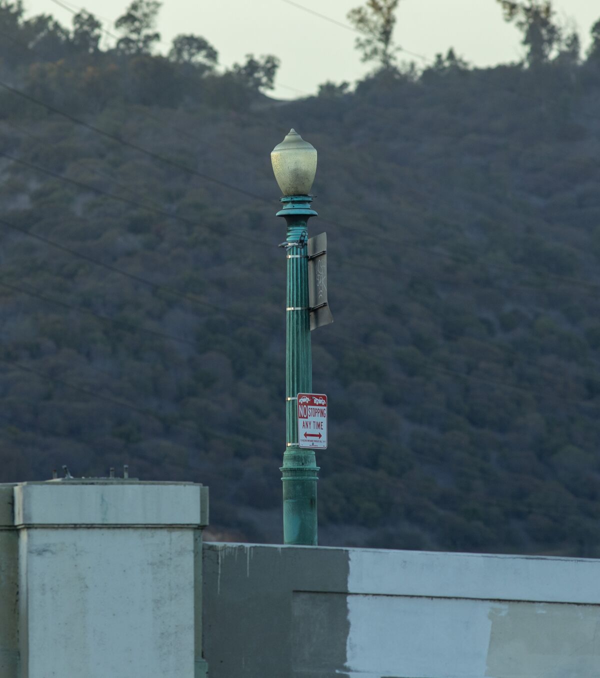 A bronze lamppost with a green-colored patina next to a bridge