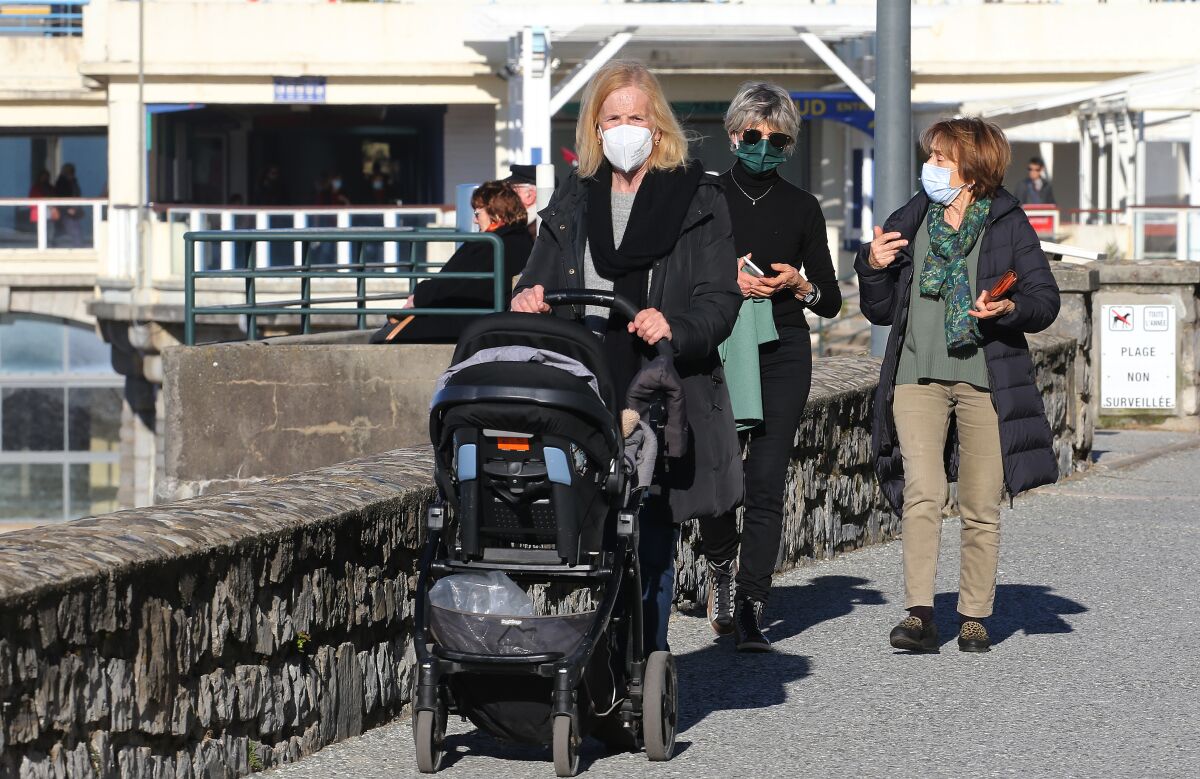 People wearing masks stroll in Saint-Jean-de-Luz southwestern France, Wednesday, Fev.2, 2022. England, France, Ireland, the Netherlands and several Nordic countries have taken steps to end or loosen their restrictions. Step by step, many countries are easing their COVID-19 restrictions amid hopes the omicron wave may have passed its peak. (AP Photo/Bob Edme)