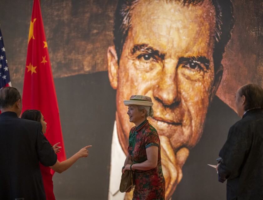 尼克松总统大画像和美国和中国国旗前的女人