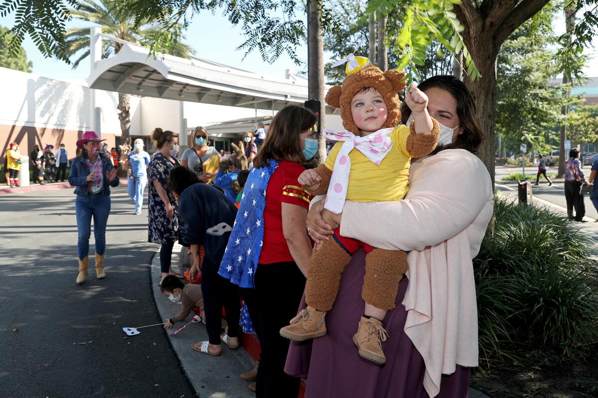 Charlie Niedermayer, 16 months old, and his mother Monique stand in the shade as they wait for the parade.