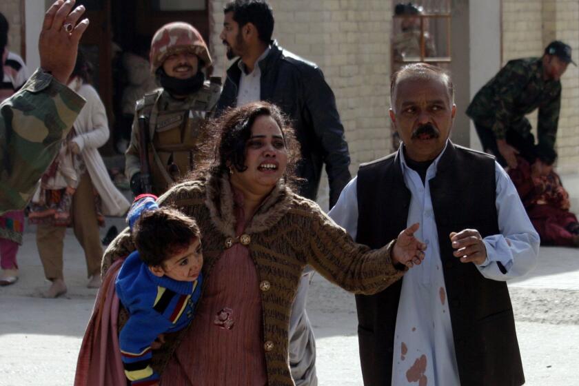 A man helps an injured woman and a child following an attack on a church in Quetta, Pakistan, Sunday, Dec. 17, 2017. Two suicide bombers attacked the church when hundreds of worshippers were attending services ahead of Christmas. (AP Photo/Arshad Butt)