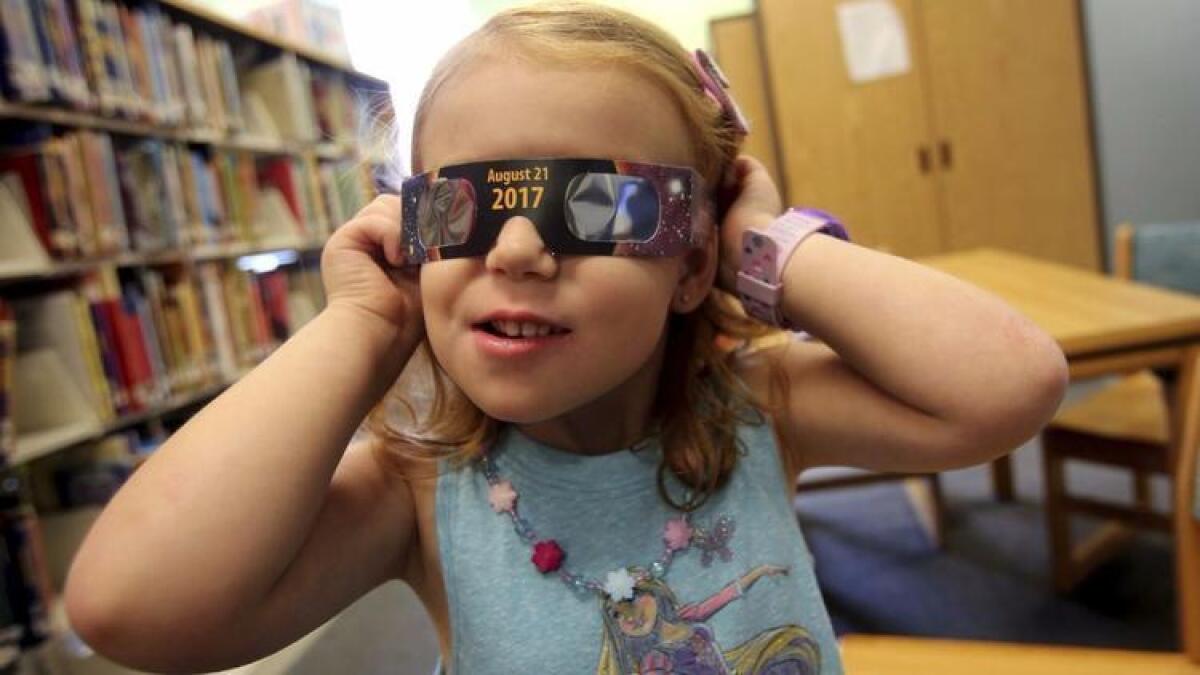 Emmalyn Johnson (3) se prueba unas gafas para eclipses en Mauney Memorial Library, en Kings Mountain, Carolina del Norte.
