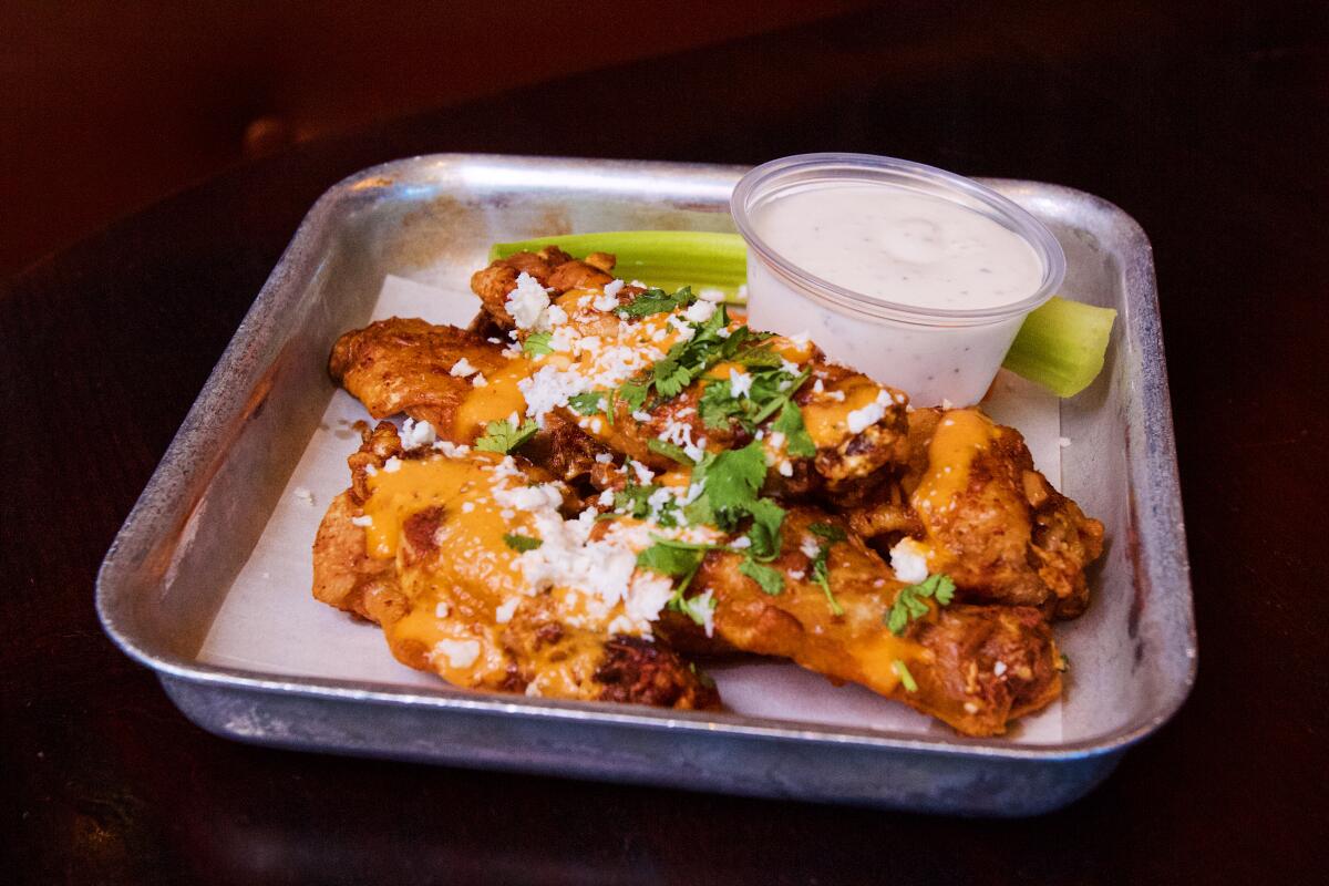 A pile of six esquites-flavored wings topped with cotija cheese and cilantro.